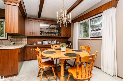 Dining area featuring wood-finish cabinetry, a built-in display hutch, tiled countertops, and a decorative chandelier - 14231 80 Street, Edmonton, AB 