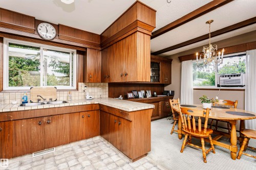 Kitchen and dining area featuring wood-finish cabinetry, tile countertops, and a window above the sink - 14231 80 Street, Edmonton, AB 
