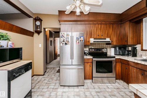 Kitchen featuring wood-finish cabinetry, stainless steel refrigerator, stainless steel range, and tile flooring - 14231 80 Street, Edmonton, AB 