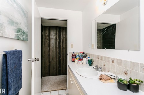 Bathroom featuring a white vanity with an integrated sink, chrome faucet, and tiled backsplash - 14231 80 Street, Edmonton, AB 