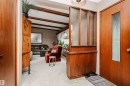 Entryway featuring a wood-panel accent wall with obscured glass panels, a wood-finish entry door with a rectangular obscured glass insert, and neutral-toned carpeting - 14231 80 Street, Edmonton, AB 