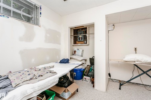 Unfinished interior space featuring a window with blinds, exposed electrical panel within an alcove, and light-colored flooring - 14231 80 Street, Edmonton, AB 