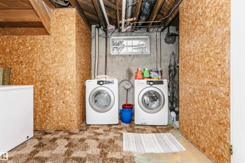 Basement laundry area featuring a concrete wall, a small window, and exposed ceiling joists - 14231 80 Street, Edmonton, AB 