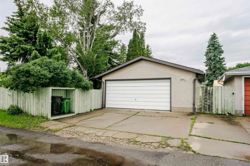 Detached garage with a sectional white door, stucco exterior, and asphalt shingle roof - 14231 80 Street, Edmonton, AB 