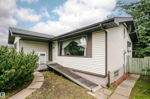 Single-story residence featuring light-colored siding and dark trim, gabled roofline, and a prominent front window - 14231 80 Street, Edmonton, AB 