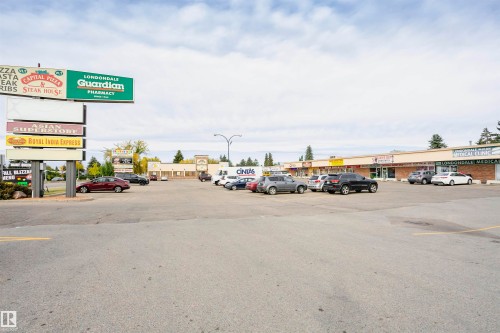 Commercial strip mall featuring multiple retail units, a prominent pylon sign, and a paved parking lot - 14231 80 Street, Edmonton, AB 