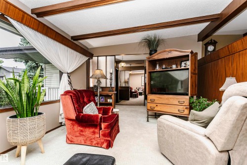 Living area featuring wood beam ceiling accents, a large picture window, and wood paneling - 14231 80 Street, Edmonton, AB 