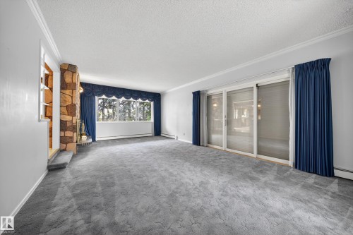 Spacious living area featuring a stone-clad fireplace and large sliding glass doors - 707 65 Avenue, Edmonton, AB 