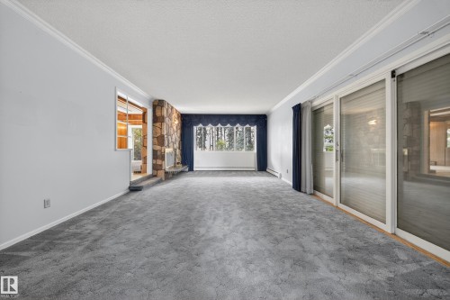 Living area featuring a stone fireplace, broad picture window, and sliding glass doors - 707 65 Avenue, Edmonton, AB 