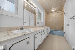 Bathroom featuring a double vanity with stone-finish countertop, dual sinks, and white cabinetry - 