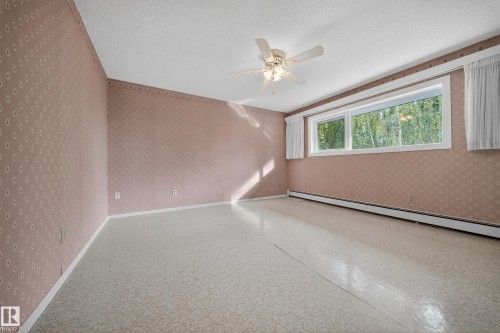 Spacious room featuring patterned wallpaper, a textured ceiling, and patterned resilient flooring - 707 65 Avenue, Edmonton, AB 