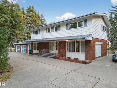 Two-story residence featuring brick and siding exterior, multiple garage doors, and a covered front entry - 707 65 Avenue, Edmonton, AB 