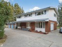 Two-story residence featuring brick and siding exterior, multiple garage doors, and a covered front entry - 707 65 Avenue, Edmonton, AB 