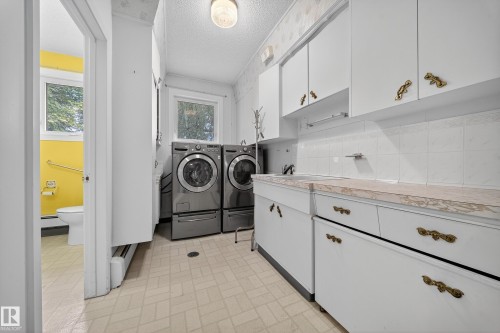 Laundry area featuring light-toned flooring, white cabinetry with ornate hardware, and a window for natural light - 707 65 Avenue, Edmonton, AB 