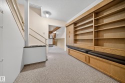 Built-in shelving with integrated bench seating and storage cabinetry, light-toned carpeting, and a staircase with white painted balusters - 