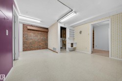 Spacious room with light-colored flooring, exposed brick accent wall, built-in shelving, and multiple doorways - 