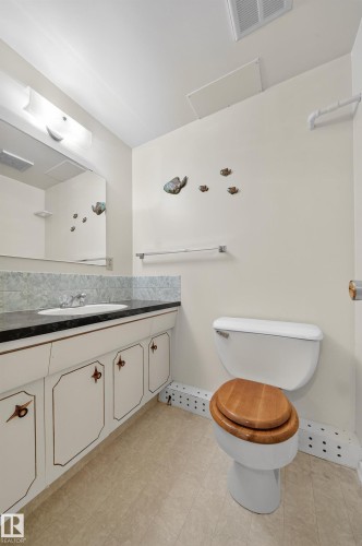 Bathroom featuring a vanity with a dark countertop, an undermount sink, and a mirrored medicine cabinet - 707 65 Avenue, Edmonton, AB 