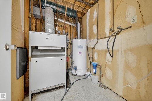 Utility area featuring a water heater, furnace, copper piping, and a water filtration system - 707 65 Avenue, Edmonton, AB 