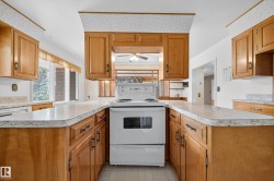 Kitchen featuring an electric range, wood cabinetry, light countertops, and a window - 
