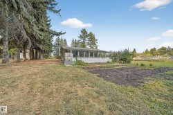 Expansive exterior featuring a screened porch, mature perimeter trees, and a prepared garden area - 