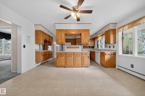 Spacious kitchen featuring extensive wood cabinetry, light-toned tiled flooring, and a central island with a multi-level countertop - 707 65 Avenue, Edmonton, AB 
