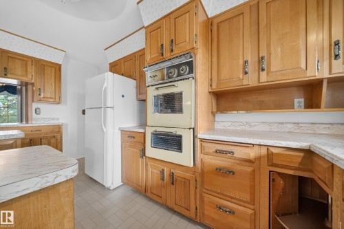 Kitchen featuring wood cabinetry, laminate countertops, a double wall oven, and tile flooring - 707 65 Avenue, Edmonton, AB 