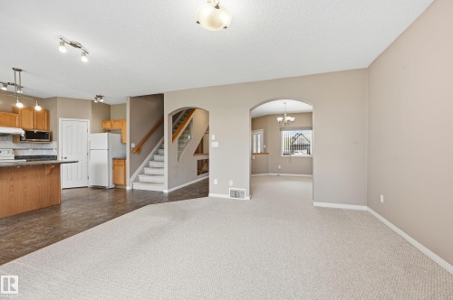 Spacious main living area featuring light-toned carpeting, neutral wall colors, and an arched entryway - 7460 Singer Landing, Edmonton, AB 
