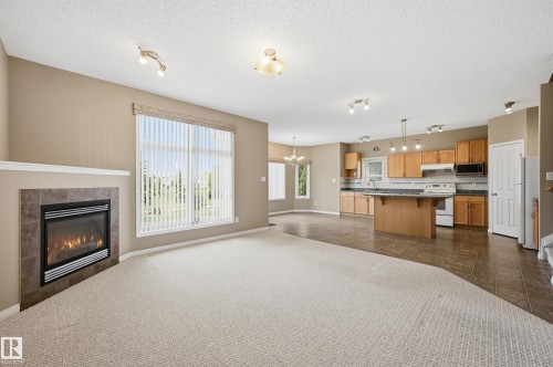 Living area featuring a fireplace with a tiled surround and mantel shelf - 7460 Singer Landing, Edmonton, AB 