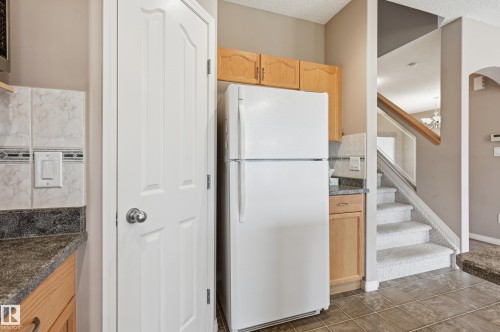 Kitchen featuring granite-look countertops, light wood cabinetry, and a tile backsplash with decorative accent tiles - 7460 Singer Landing, Edmonton, AB 