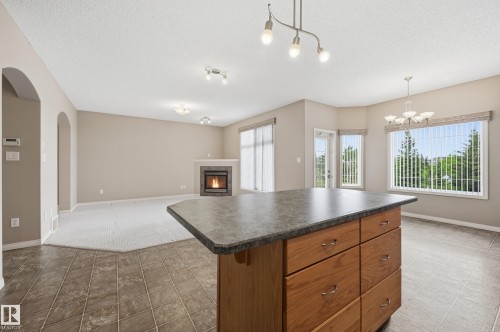 Kitchen island with wood-finish cabinetry and a dark countertop - 7460 Singer Landing, Edmonton, AB 