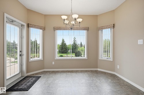 Bright dining area featuring a full-light exterior door and multiple windows with vertical blinds - 7460 Singer Landing, Edmonton, AB 