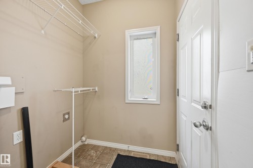 Utility room featuring durable tile flooring, a white paneled door, and a frosted window - 7460 Singer Landing, Edmonton, AB 