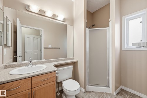 Bathroom featuring a wood-finish vanity with an integrated sink and laminate countertop - 7460 Singer Landing, Edmonton, AB 