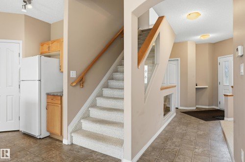 Carpeted staircase with glass panel railing and wood handrail - 7460 Singer Landing, Edmonton, AB 