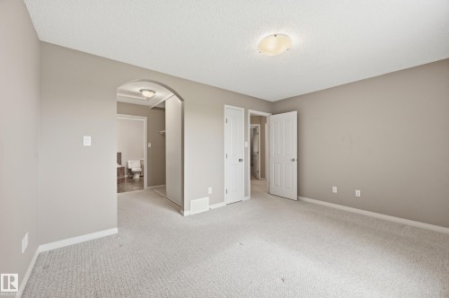 Spacious room featuring light-toned carpeting, neutral wall paint, and white trim - 7460 Singer Landing, Edmonton, AB 