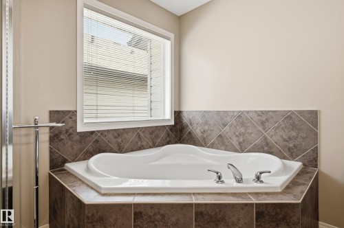 Built-in corner soaking tub featuring a white basin and polished chrome fixtures - 7460 Singer Landing, Edmonton, AB 