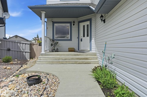 Inviting entryway featuring a white paneled door with glass inserts, concrete steps, and a complementary concrete walkway - 7460 Singer Landing, Edmonton, AB 