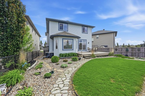 Expansive backyard featuring a lush lawn, a stone pathway, and a multi-level wooden deck - 7460 Singer Landing, Edmonton, AB 