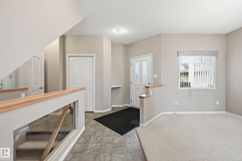 Entryway featuring tile flooring, a front door with decorative glass inserts, and a built-in wall niche - 7460 Singer Landing, Edmonton, AB 