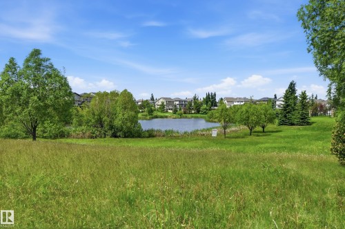Expansive green space featuring a natural pond surrounded by mature trees - 7460 Singer Landing, Edmonton, AB 