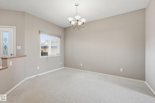 Neutral tone walls with an overhead chandelier and textured ceiling - 7460 Singer Landing, Edmonton, AB 