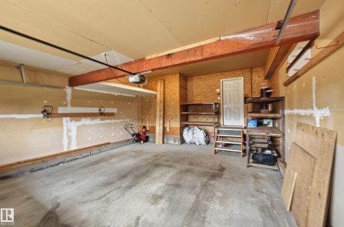Concrete flooring garage with an overhead automatic door mechanism, built-in shelving, and a side entry door - 7460 Singer Landing, Edmonton, AB 