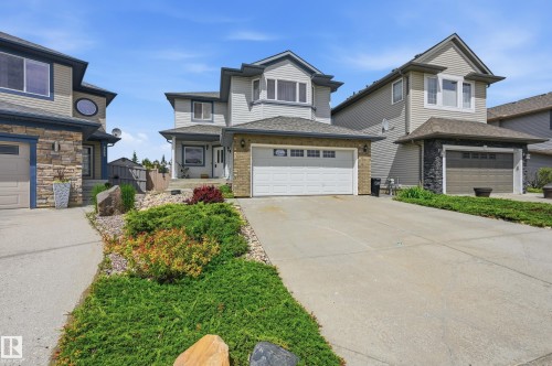 Two-story residence featuring light gray siding, a prominent bay window, and an attached two-car garage with a white door - 7460 Singer Landing, Edmonton, AB 