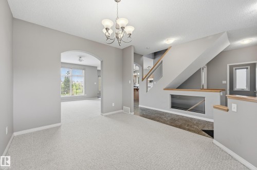 Inviting interior featuring light gray walls, plush carpet flooring, a chandelier, and an arched doorway - 7460 Singer Landing, Edmonton, AB 
