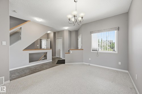 Open concept living area featuring light gray walls, plush carpeting, and a tiled entry - 7460 Singer Landing, Edmonton, AB 