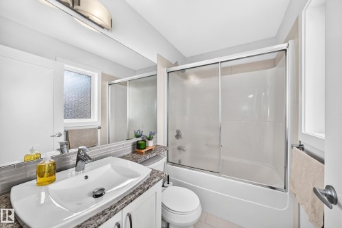Bathroom featuring a vanity with a white vessel sink, a granite-finish countertop, and a full-width mirror - 2433 Glenridding Boulevard, Edmonton, AB 
