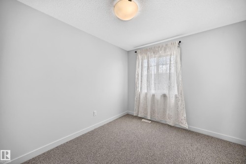 Light gray walls complement the neutral gray carpeting in this room featuring a ceiling-mounted light fixture and a window with white trim - 2433 Glenridding Boulevard, Edmonton, AB 