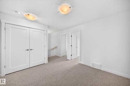 Open space featuring wall-to-wall carpeting, white interior doors with contemporary hardware, and overhead flush-mount lighting fixtures - 2433 Glenridding Boulevard, Edmonton, AB 