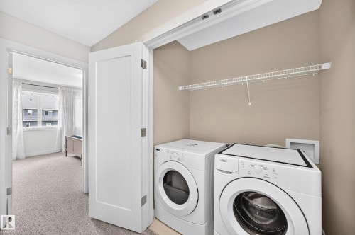 Dedicated laundry area featuring a wire storage shelf, light neutral wall paint, and carpeted flooring - 2433 Glenridding Boulevard, Edmonton, AB 