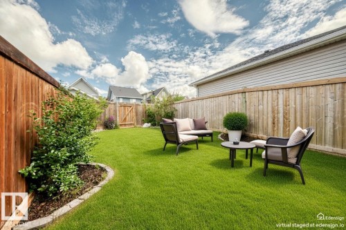 Expansive backyard featuring a green lawn, wood privacy fencing, and a decorative garden bed with established plantings - 2433 Glenridding Boulevard, Edmonton, AB 